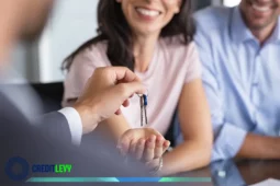 Pessoa entregando chaves nas mãos de uma mulher sorridente, simbolizando a compra ou aquisição de imóveis por um casal feliz.