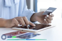 Pessoa usando um tablet com uma mão e segurando um cartão de crédito com a outra, representando compras online e controle financeiro digital.