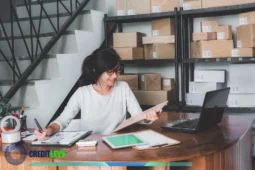 Profissional autônoma organizando pedidos e revisando planilhas, simbolizando a organização das finanças para autônomos em ambiente de trabalho.