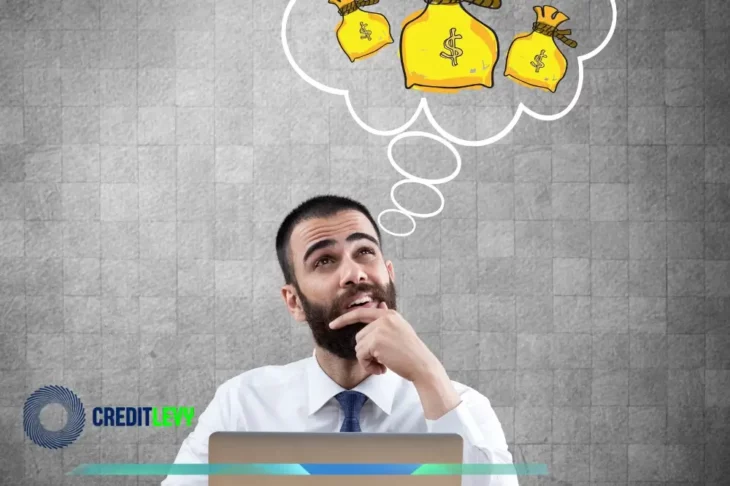 Hombre pensativo frente a un portátil con un globo de pensamiento lleno de bolsas de dinero, representando el interés por aprender sobre renta variable para principiantes.