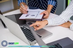 Duas pessoas analisando dados financeiros em notebook e prancheta com gráficos, representando o planejamento e estudo para investir no Tesouro Direto.