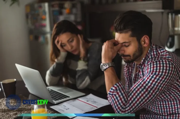 Pareja preocupada revisando cuentas y documentos frente al ordenador, representando el desafío de cómo salir de las deudas de forma definitiva.