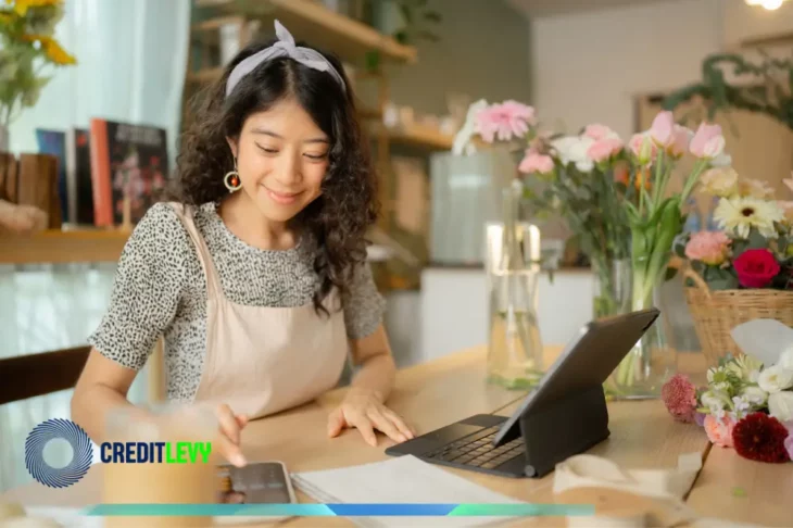 Mujer gestionando su negocio de flores con una tablet y un móvil, representando el manejo de finanzas para autónomos y la administración de pequeños negocios.