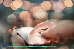 Pessoa usando smartphone com efeito de luzes desfocado, ilustrando o uso do Celular Seguro.