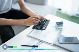 Persona calculando finanzas con gráficos, calculadora y maqueta de casa, representando la planeación en tiempos de alta inflación.