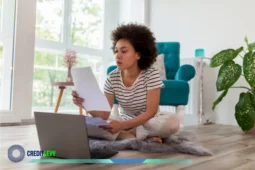 Mujer revisando documentos frente a su computadora, simbolizando la opción de refinanciar deudas para mejorar sus finanzas.