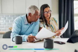 Pareja usando tableta y revisando documentos como ejemplo de gestión de finanzas digitales en el hogar.