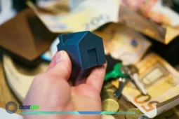 Mano sosteniendo una casa en miniatura sobre billetes y llaves, simbolizando el Infonavit 2025 y los créditos para vivienda ofrecidos a trabajadores en México.