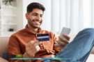 Homem usando cartão e celular para acumular milhas no programa Smiles.