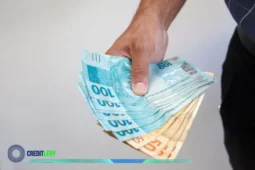 Homem segurando várias cédulas de dinheiro brasileiro, ilustrando situações de saque e dificuldades quando o FGTS bloqueado impede o acesso ao saldo.