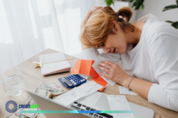 Pessoa preocupada organizando contas e recibos na mesa, com calculadora e dinheiro, antes de negociar dívida com o Banco do Brasil.